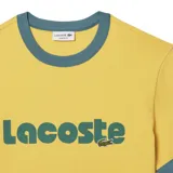 Remera amarilla de Lacoste con cuello redondo y mangas cortas con ribete azul. Estampa frontal con el logo de la marca en verde.