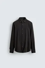 Camisa de corte relajado confeccionada en tejido de algodón con textura. Presenta cuello italiano, manga larga con puños abotonados y cierre frontal mediante botonadura.