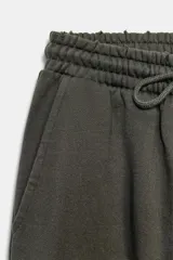Pantalón de tiro medio con pierna ancha, confeccionado en tejido lavado. Presenta cintura elástica ajustable con cordones, bolsillos laterales y bolsillos traseros decorados con estrellas y aplicaciones de tachas. El diseño cuenta con terminaciones desflecadas en el ruedo.
