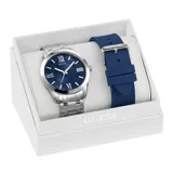 Reloj analógico Guess con caja de acero inoxidable plateado y esfera azul con acabado sunray, índices y números romanos. Incluye una correa de acero inoxidable plateado y una correa de silicona azul intercambiable.