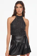 Top de punto estilo halter, con cuello alto ajustado y diseño sin mangas. Confeccionado artesanalmente en Uruguay con mezcla de algodón y acrílico, presenta acabado texturizado en color negro con sutiles destellos plateados.