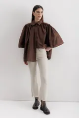 Pantalón de jean color marrón óxido, tiro medio, corte ajustado en muslos y ligeramente acampanado en la parte inferior (bootcut/flare), con bajo desflecado.