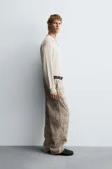 Pantalón de corte relajado confeccionado en tejido ligero de algodón con estampado abstracto de efecto lavado. Presenta cintura elástica, bolsillos frontales y bolsillos traseros de plastrón, con cierre frontal de cremallera y botón.
