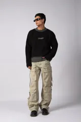 Sweater de punto acanalado con diseño degradado de negro a gris en el cuello y el ruedo. Presenta un corte regular y un pequeño bordado central en el pecho.