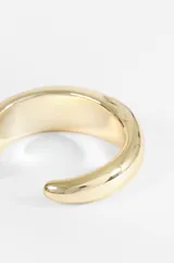 Pulsera tipo cuff de diseño minimalista y voluminoso con acabado metálico brillante.