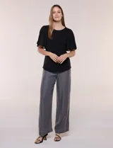Blusa blanca con escote redondo y mangas cortas estilo mariposa confeccionadas en tela plisada translúcida.