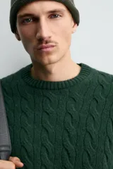 Jersey de punto con diseño de trenzas verticales, cuello redondo y manga larga. Presenta un ajuste regular y acabados en rib en cuello, puños y ruedo.