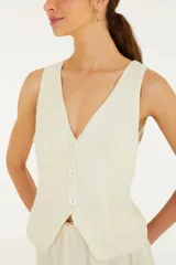 Chaleco color crema con escote en V y cierre frontal con botones. Confeccionado en viscosa, lino y algodón.