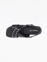 Sandalias negras de cuero sintético con tiras cruzadas y detalles de tachas plateadas.