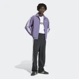 Pantalon deportivo Adidas modelo Adibreak, de corte recto y color negro. Presenta las icónicas tres tiras blancas laterales y botones a presión a lo largo de las piernas, con logo de la marca bordado en la parte inferior.