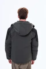 Campera técnica con capucha desmontable, diseño bicolor en negro y gris. Cuenta con cierre frontal termosellado, bolsillos laterales y bolsillo en el pecho con cierre, ideal para protección contra el viento y el frío.