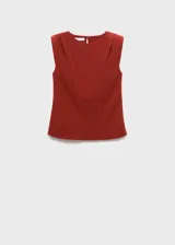 Blusa de color bordó con cuello barco y hombreras marcadas que crean una silueta estructurada. Presenta un diseño recto sin mangas con detalle fruncido en los hombros.