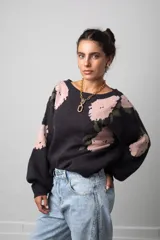 Buzo de punto color negro con estampado floral en tonos rosado y verde, de corte oversize, cuello redondo y mangas globo.