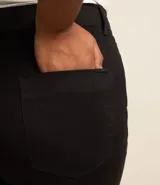 Pantalón skinny de sarga color negro, con cintura con trabillas, elástico regulador interno, cierre por cremallera y botón, y bolsillos.