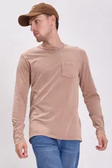 Remera de manga larga en color tostado con efecto lavado, cuello redondo y bolsillo frontal en el pecho.