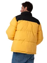 Campera puffer Caterpillar de diseño bicolor en amarillo y negro, con cierre frontal completo, cuello alto y bolsillos laterales con cierre. Presenta el logo de la marca estampado en el pecho y puños ajustables.