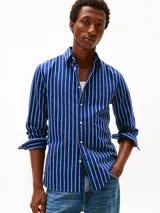 Camisa Tommy Hilfiger de corte regular, confeccionada en tejido Oxford de algodón con textura y diseño de rayas verticales azules y blancas. Cuenta con cuello abotonado, mangas largas con puños abotonados y logo bordado en el pecho.