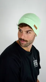 Gorro tipo beanie de punto color verde agua, con doblez en el borde y etiqueta de cuero sintético con el logo de la marca Duxon.