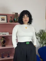 Pantalón sastrero de corte amplio y tiro alto, confeccionado en viscosa. Presenta pinzas en la cintura y un aplique decorativo de acrílico en el centro de la pretina.