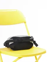 Riñonera gris de poliéster con cierre naranja y logo de la marca Rusty en negro.