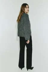 Pantalón sastrero negro de corte acampanado, con cierre, botón oculto y corchetes. Incluye bolsillos al bies y bolsillos traseros ribeteados, con pliegues en la parte delantera y trasera de las piernas.