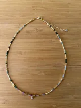 Collar corto dorado con cuentas de turmalina multicolor y dije de cristal transparente.