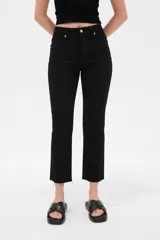 Pantalón jean negro de tiro alto y corte recto, con bolsillos y terminación deshilachada en los tobillos.