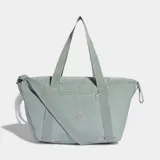 Bolso deportivo Adidas de diseño minimalista en color gris, con correas de hombro integradas y correa ajustable extraíble. Cuenta con un bolsillo frontal con cierre y logo de la marca estampado en tono sobre tono.