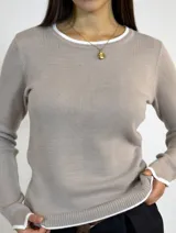 Buzo de tejido de punto en color camel, con cuello redondo y detalles de terminaciones en color blanco en cuello, puños y ruedo. Presenta un corte recto y mangas largas.