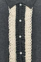 Chaqueta de punto gris oscuro con cuello solapa y manga larga. Presenta un diseño frontal con detalle de puntilla en color crema a contraste y cierre con botones.