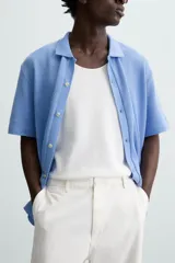 Cárdigan celeste de tejido de algodón con estructura tipo waffle. Tiene cuello solapa, manga corta y cierre frontal con botones.