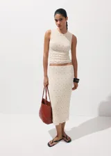 Falda midi de corte recto, confeccionada en tejido texturizado de color beige con pequeñas tachas metálicas distribuidas en el diseño y forro interior.