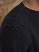 Sweater de cuello redondo confeccionado en algodón grueso con textura acanalada, de corte clásico y manga larga.