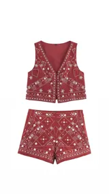 Conjunto de dos piezas compuesto por un chaleco con cierre frontal de botones y un short de tiro alto. Ambas prendas son de color rojo y presentan un elaborado bordado geométrico con detalles de espejos circulares incrustados.