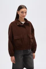 Campera corta marrón de pana, con cuello alto, cierre frontal con broches a presión, bolsillos plaqué con solapa y puños elásticos.