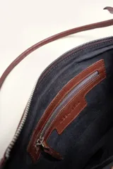 Cartera bandolera de cuero marrón con forma relajada, diseño de costuras curvas y detalles de nudos hechos a mano en las asas.