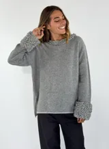 Sweater gris de manga larga con cuello redondo y puños con detalle de volados de lana rizada.