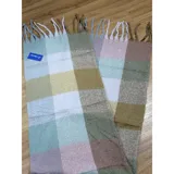 Bufanda rectangular de tejido grueso con diseño de cuadros en tonos azul, naranja, gris y beige, terminada con flecos en los extremos.