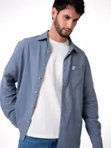 Camisa de manga larga con corte relajado, confeccionada en algodón con textura ligera. Presenta cierre frontal con botones, cuello clásico, puños abotonados y un bolsillo en el pecho con etiqueta de la marca Cat.