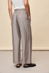 Pantalón gris de corte amplio y silueta fluida, con cintura elástica y cordón ajustable.