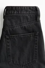Jean wide leg de tiro alto en denim de algodón negro, con diseño de cinco bolsillos, perneras amplias y cierre frontal con botón y cremallera.