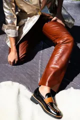 Mocasines de cuero en color dorado con detalles en marrón, con diseño bicolor y costuras artesanales expuestas en el empeine.