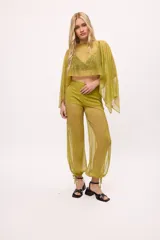 Poncho corto de chiffon color amarillo verdoso con textura plisada y brillo metálico. Presenta un cuello redondo y mangas amplias tipo capa.