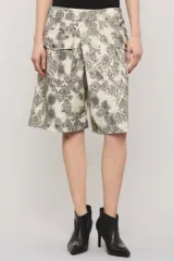 Bermuda de gabardina de calce relajado, tiro largo, con estampado estilo paisley en tonos beige y negro, y bolsillos delanteros estilo cargo con broches metálicos.
