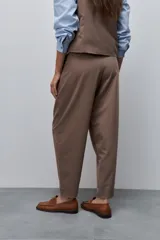 Pantalón marrón de tiro alto y silueta amplia, confeccionado con pinzas en el frente y bolsillos laterales.