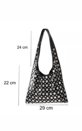 Cartera tipo hobo de color negro con acabado brillante, decorada completamente con remaches metálicos circulares de diversos tamaños.
