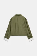 Cazadora verde militar de corte crop, confeccionada en hilatura con lino, con cuello solapa, manga larga y bolsillos de plastrón en el delantero. Cuenta con cierre frontal de botones oscuros y detalles a rayas en contraste en los puños y el interior.
