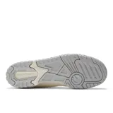 Championes New Balance 550 color crema con detalles en gris en la suela y logo.