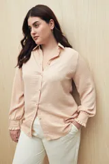 Camisa color café con textura sutil, cuello clásico, botones forrados a tono y mangas largas con puños fruncidos.