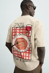 Camiseta relaxed fit color beige, con cuello redondo y manga corta. Presenta un bordado y estampado combinado a contraste en el delantero y la espalda.